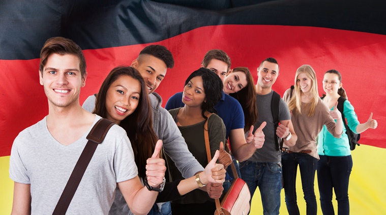 Group Of Multi Ethnic Students Standing In Front Of German Flag Showing Thumb Up